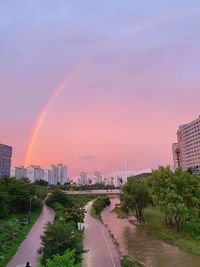 Road amidst buildings against sky during sunset
