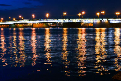 Illuminated bridge over water at night