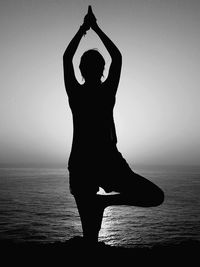 Silhouette woman standing by sea against clear sky