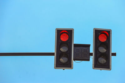 Low angle view of road signals against clear blue sky