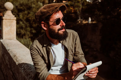 Man writing in book while sitting outdoors