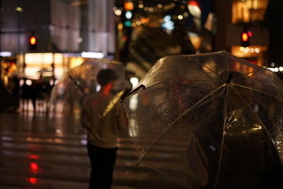 People walking on wet street in city during rainy season