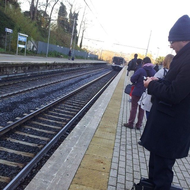 railroad track, rail transportation, men, transportation, lifestyles, railroad station platform, public transportation, rear view, railroad station, the way forward, walking, person, leisure activity, travel, sky, built structure, standing, railway track