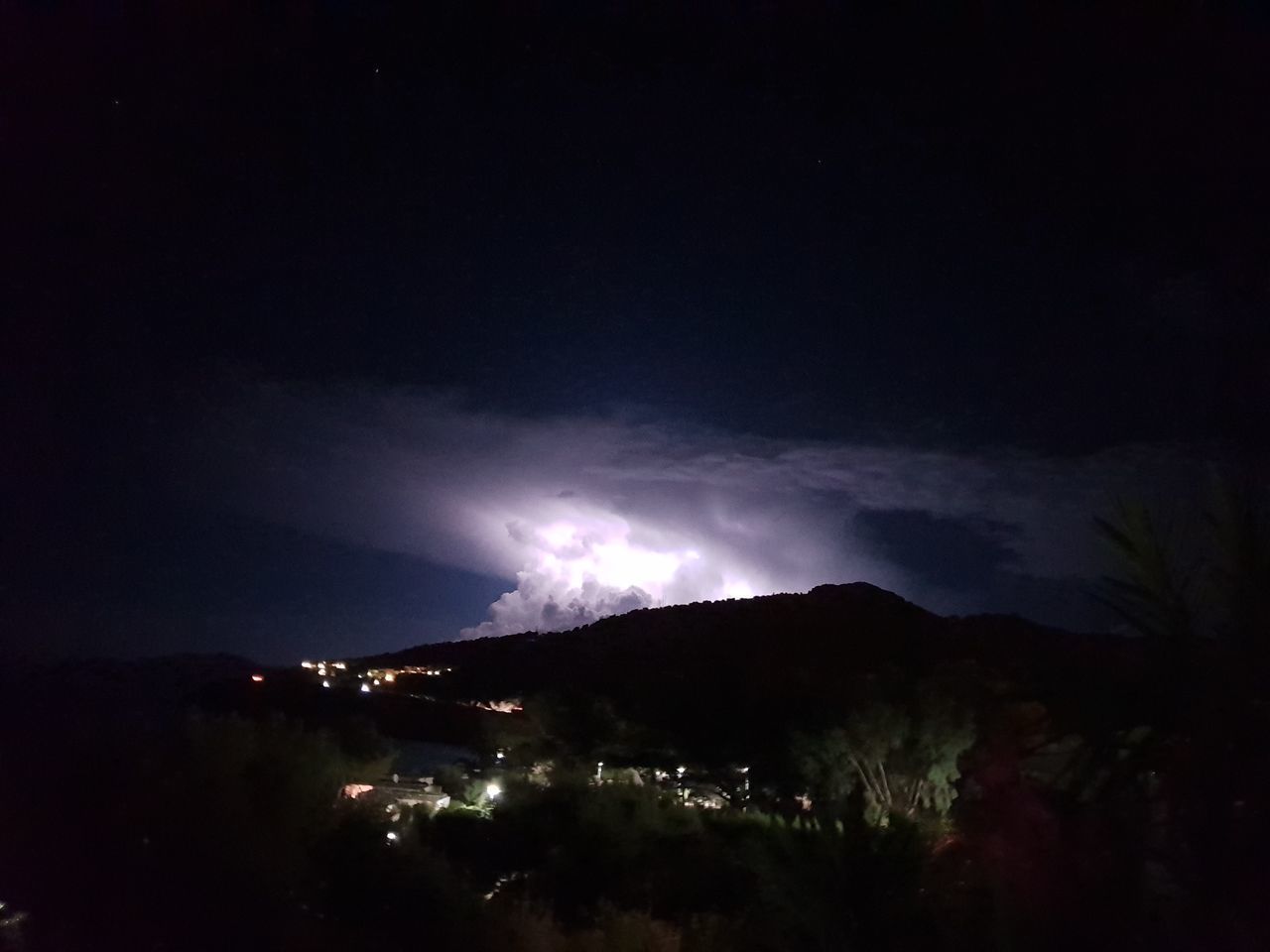 PANORAMIC VIEW OF ILLUMINATED MOUNTAINS AGAINST SKY AT NIGHT