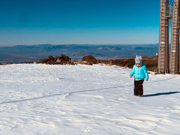 Rear view of man walking on snow covered landscape