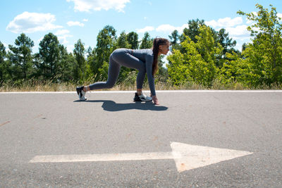 Full length of woman bending on road against sky