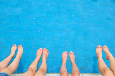 Low section of people sitting at poolside