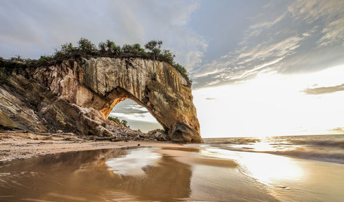 Rock formation on beach against sky