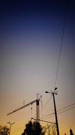 Low angle view of silhouette electricity pylon against sky during sunset