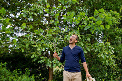 Young man eating leaves while standing against trees