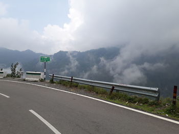 Road sign by mountains against sky