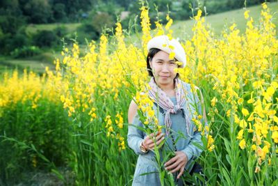 Portrait of smiling young woman standing in yellow flower