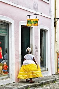 Rear view of woman walking against yellow building