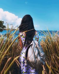 Rear view of woman standing by sea against sky