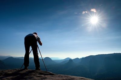 Professional photographer with tripod on cliff and thinking. dreamy fogy land, beautiful valley