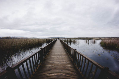 Footbridge over lake against sky