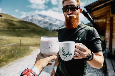 Man toasting drink with friend on field