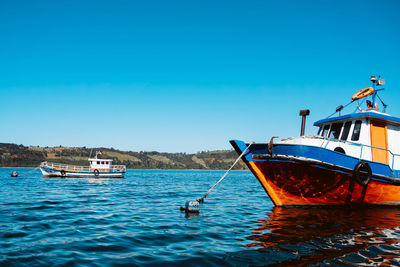 Boat in sea against clear blue sky