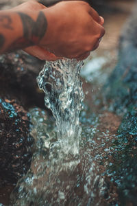 Close-up of hand holding water over stream