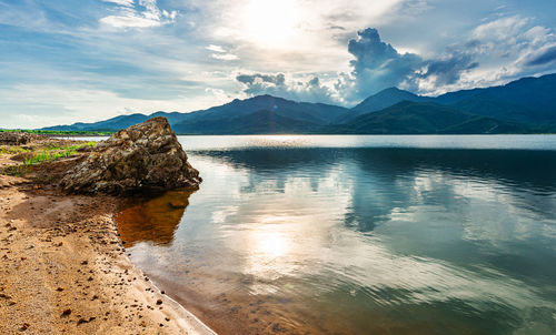 Scenic view of lake by mountains against sky