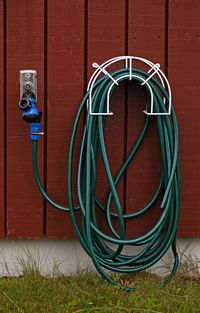 Green water hose hanging on wall