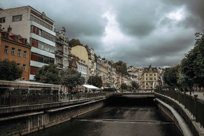 Bridge over canal amidst buildings in city against sky