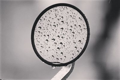 Close-up of wet glass against sky