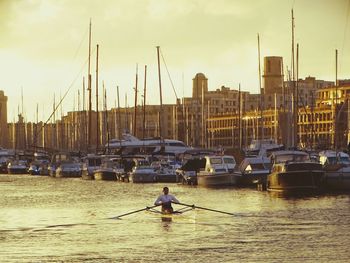 Sailboats moored at harbor against sky during sunset