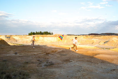 Rear view of people walking at beach against sky