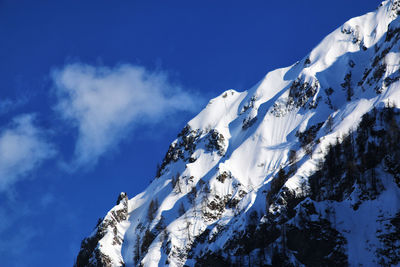 Low angle view of snow covered mountain against blue sky