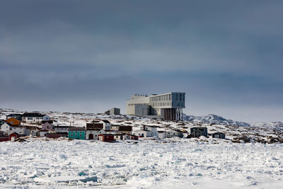 Snow covered houses against sky during sunny day