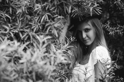 Young woman wearing hat by plants in forest