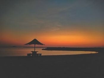 Silhouette beach by sea against sky during sunset