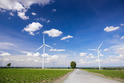 Wind turbines on field against sky