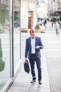 Mature businessman using smart phone while standing in city