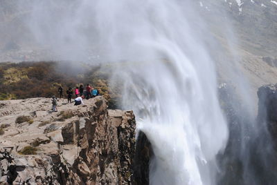 People on mountain by waterfall