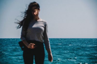 Woman standing in sea against clear sky