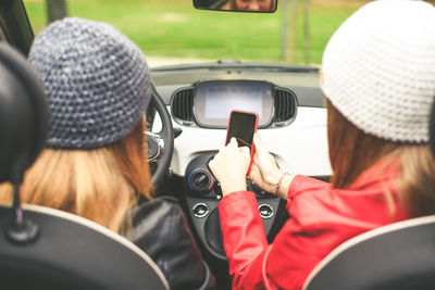 Girls sitting in the car. smiling teen in front of the steering wheel young women using smartphone