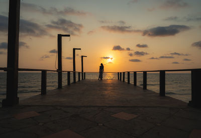 Silhouette man standing by sea against sky during sunset