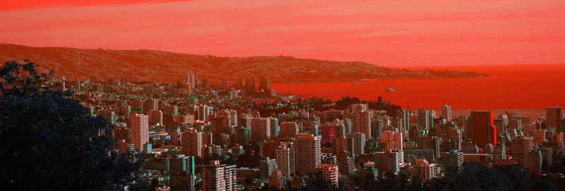 Illuminated cityscape against sky during sunset