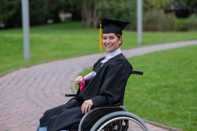 Rear view of woman wearing graduation in park