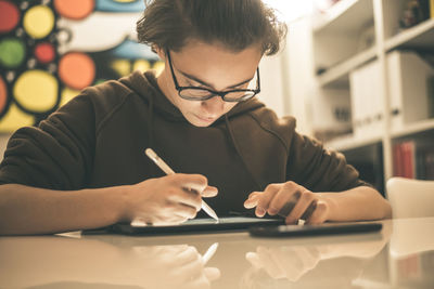 Teenager drawing with tablet and virtual pen. student doing homework with new technology devices. 