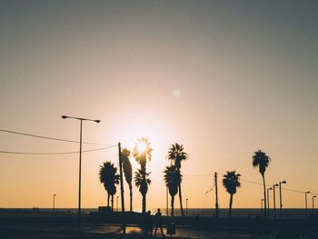 Silhouette palm trees on beach against sky during sunset