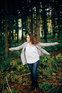 Portrait of smiling young woman standing in forest