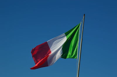 Low angle view of flag against clear blue sky