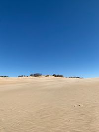 Scenic view of desert against clear blue sky