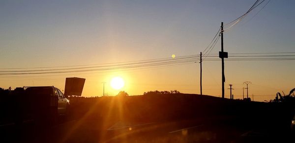 Silhouette electricity pylon against sky during sunset