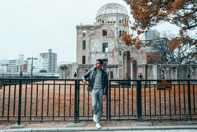 Man standing by railing against buildings in city