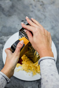 Cropped hand of person grating cheese in plate