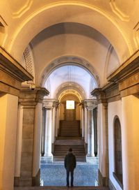 Rear view of man walking in corridor of building